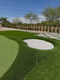 Backyard golf course with green turf, sand bunkers, and tree-lined landscape design
