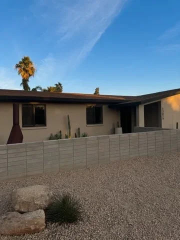 Modern home with gray composite horizontal fence and desert landscape with gravel and cacti
